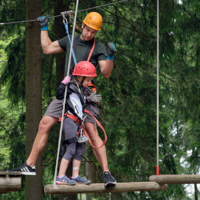 Ein Erwachsener und ein Kind klettern im Treerock Hochseilgarten